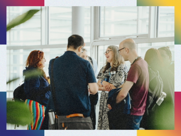 A group of people stood together talking and smiling, framed with colourful corners.