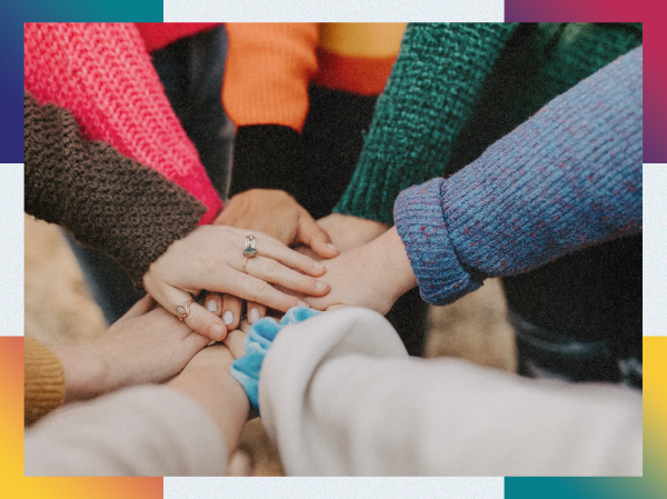 A circle of people putting their hands together, framed with colourful corners.