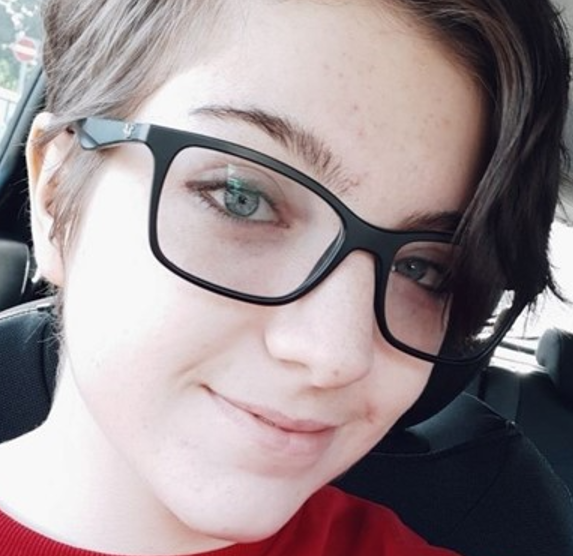 A photo of Becca smiling, wearing a dark red top.