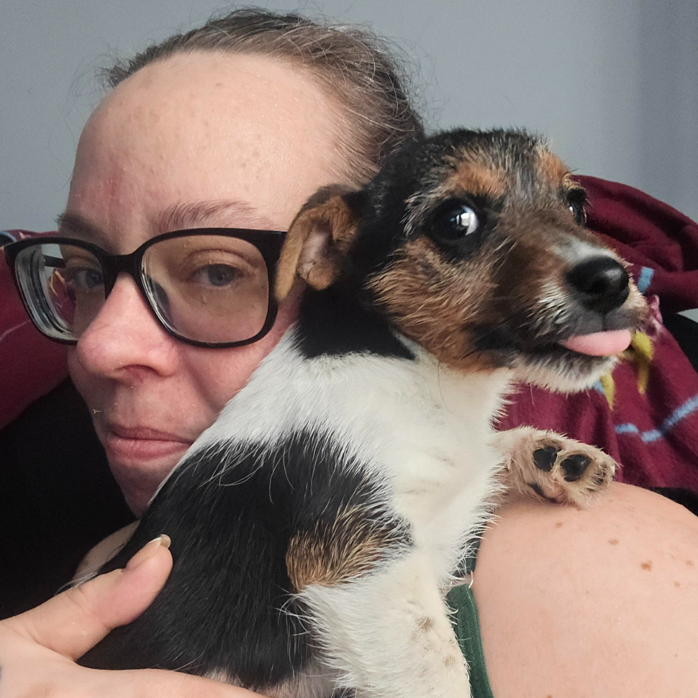 A photo of Nicky holding her dog to the camera.