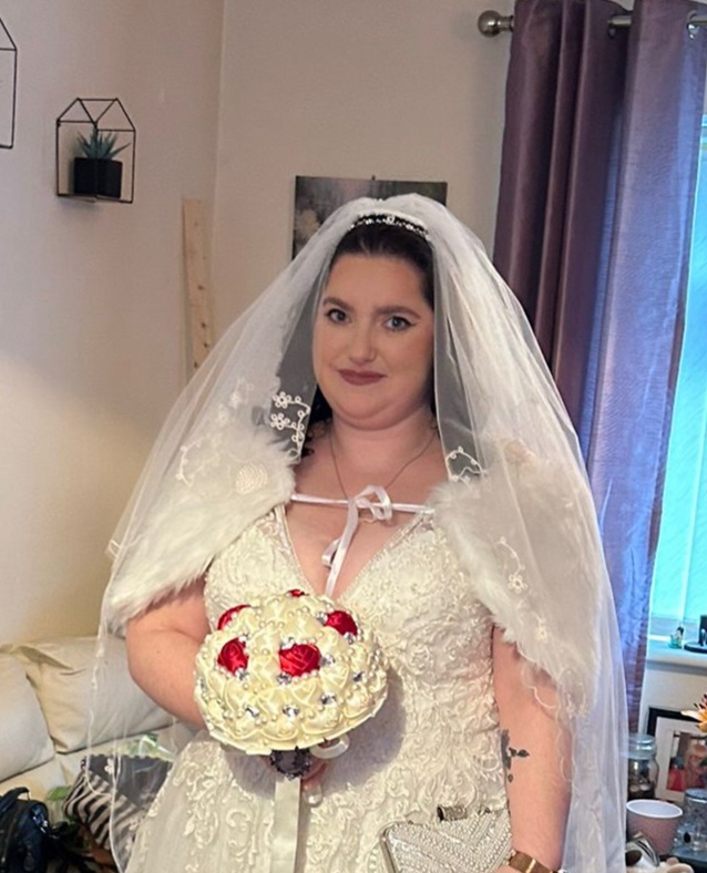 A photo of Rebecca smiling, wearing a white wedding dress and holding a bouquet.