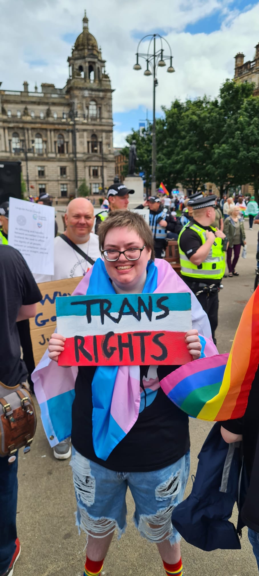 Kit on a Pride march, smiling at a camera.