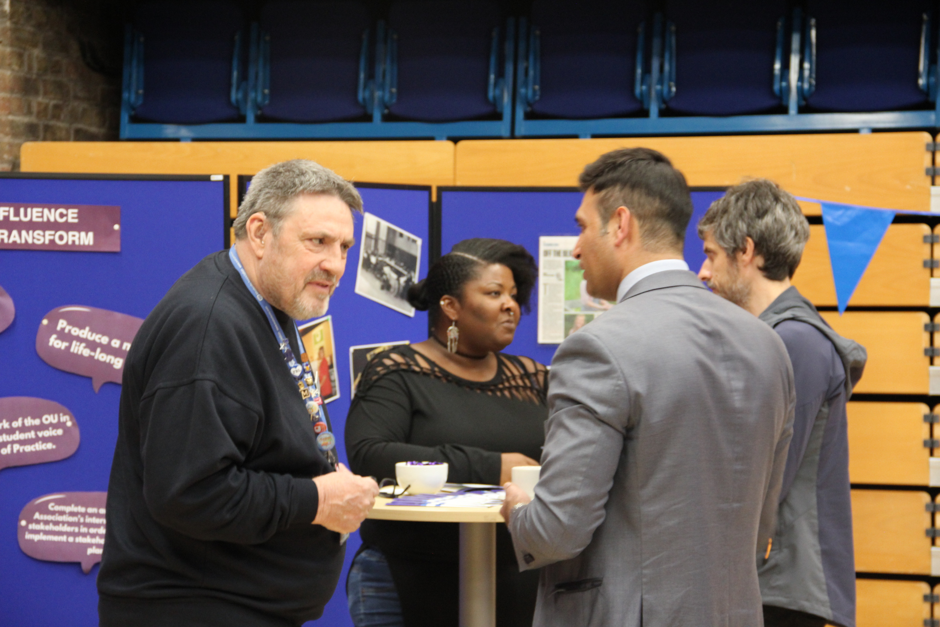 The image shows a group of students talking round a table.