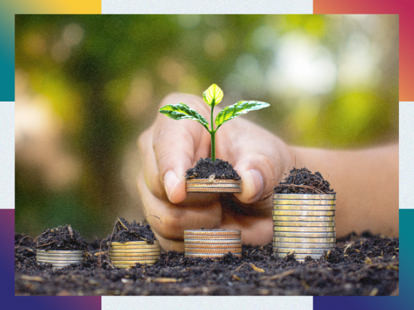Someone planting coins in soil while a tiny shoot grows out of one coin.