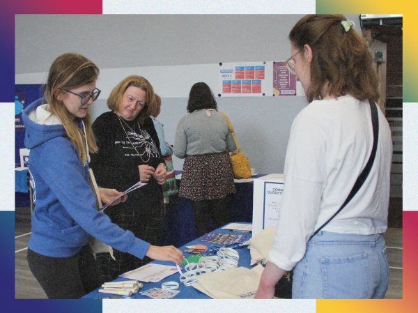 People looking at the items on a stall at an in-person event, framed with colourful corners.