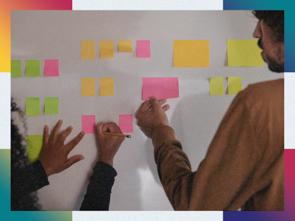 Two people sticking post-it notes on a wall.