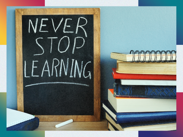 A chalkboard that reads 'never stop learning' next to a pile of books and notepads.